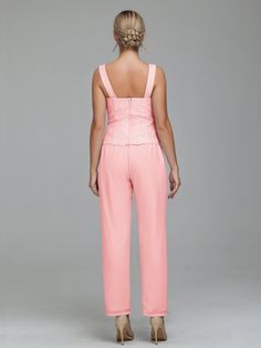 the back of a woman wearing pink pants and a halt neck top with lace detailing