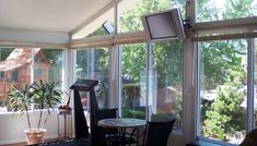 a living room filled with lots of windows next to a small table and chairs in front of a window