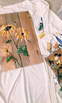 sunflowers painted on wooden planks next to paintbrushes and other art supplies