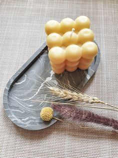 some yellow candles are sitting on a gray plate with feathers and a feather quill