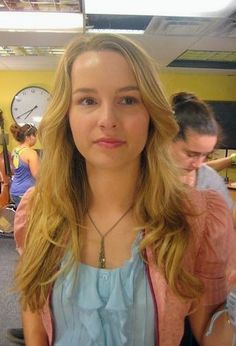 a young woman standing in an office next to a wall with clocks on the walls