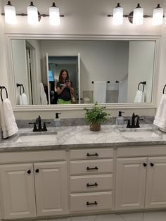 a woman takes a photo of herself in the bathroom mirror while she is taking her own picture