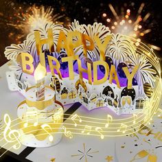 a happy birthday greeting card with fireworks and music notes on the table next to it