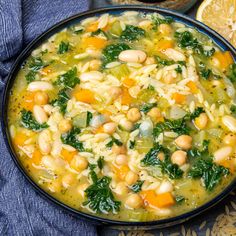 a bowl of soup with beans, spinach and carrots on a blue cloth