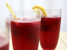 two glasses filled with red liquid and lemon wedges