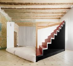 an empty room with stairs and mattresses on the floor in front of a wall