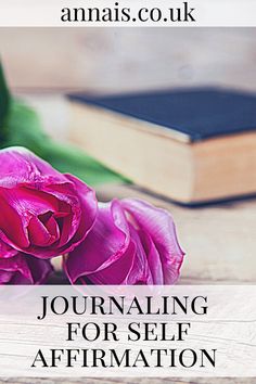 a pink rose sitting on top of a wooden table next to a book with the words journaling for self affirmation