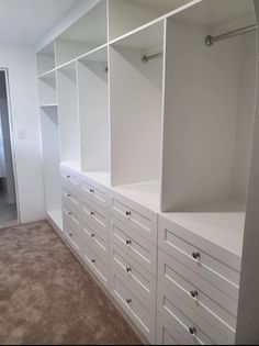 an empty room with white cabinets and carpeted flooring in the middle of it