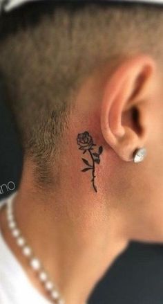 a man with a small rose tattoo on his left side behind the ear is looking at the viewer