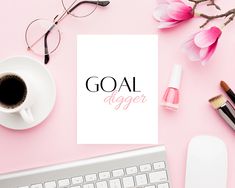 an overhead view of a desk with coffee, eyeglasses and paper that says goal digger on it