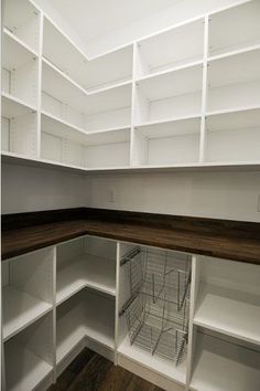 an empty pantry with white shelving and wood flooring on the side, including shelves