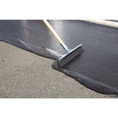 a person is using a broom to clean the asphalt