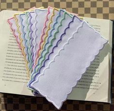 five different colored napkins sitting on top of an open book with checkered paper