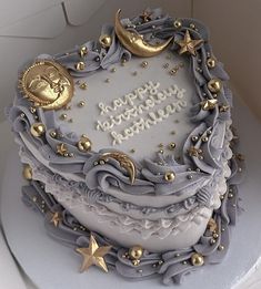 a birthday cake decorated with gold stars and moon decorations on a white tableclothed surface