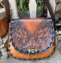 This vintage handmade leather purse is a perfect addition to any boho, western or hippie outfit. The exterior of the bag is tooled leather in a brown color. The flap is beautifully tooled and has a brass lock closureI added new lacing and a new adjustable strapthe leather was oiled and conditioned... The medium-sized hobo bag has a single leather strap in a matching brown color, adding to the overall vintage vibe of the product. This unique bag is perfect for the free-spirited cowgirl or hippie at heart. Add this beautiful piece to your collection today! Measurements are 10 inches across, 9 inches tall, the gusset is 2 inches and the strap is long so it can be worn as a shoulder or crossbody bag...the strap is adjustable Western Style Hand Tooled Brown Shoulder Bag, Western Style Brown Hand Tooled Shoulder Bag, Western Style Hand Tooled Brown Bag, Western Brown Bag With Adjustable Strap, Western Style Hand Tooled Shoulder Bag For Travel, Western Brown Shoulder Bag With Adjustable Strap, Western Style Brown Shoulder Bag With Adjustable Strap, Western Brown Satchel Shoulder Bag, Western Style Brown Satchel Bag