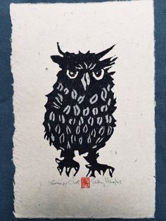 a black and white drawing of an owl sitting on top of a blue cloth covered pillow