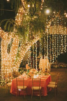 an outdoor dining area with lights strung from the trees and tables set for dinner outside