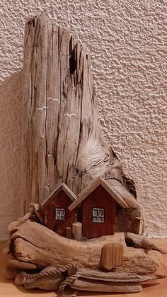 a small house made out of driftwood on a wooden table next to a wall