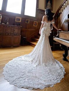 a woman standing in front of a grand piano wearing a wedding dress with an open back