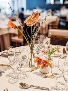 the table is set with silverware, wine glasses, and flowers in vases