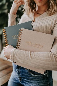 a woman holding two notebooks in her hands