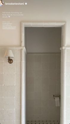 a bathroom with white tile and black dots on the floor