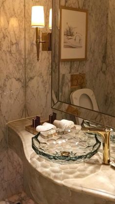 a fancy bathroom with marble counter tops and gold faucet lights on the wall