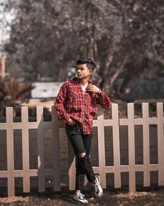 a man leaning against a fence with his hands on his hips