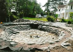 an outdoor fire pit surrounded by rocks and gravel in the middle of a driveway area