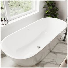 a large white bathtub sitting next to a window in a bathroom with marble counter tops