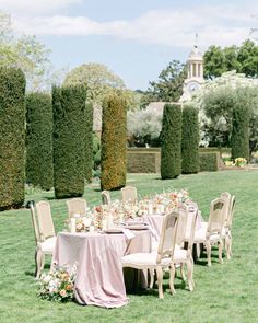 an outdoor table set up with flowers and greenery for a formal dinner in the park