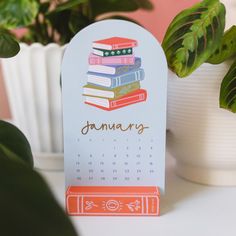 a calendar with books on it sitting next to a potted plant