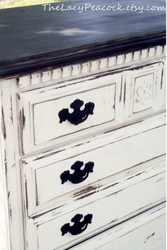 an old white dresser with black knobs