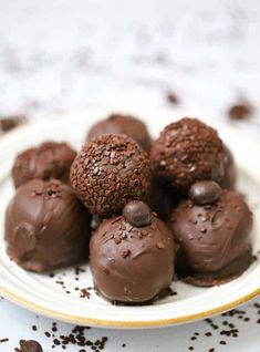 chocolate truffles on a white plate with sprinkles around the edges