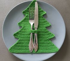 a fork and knife on a plate with a crocheted christmas tree placemat