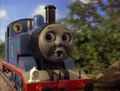 a thomas the tank engine is making a funny face as it travels down the tracks