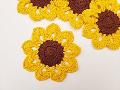 three crocheted yellow and brown flowers on a white surface