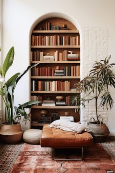 a living room with bookshelves, plants and an ottoman in front of it