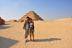 two people standing in front of a pyramid