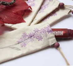 some red and purple leaves are on the table next to two small bags with flowers