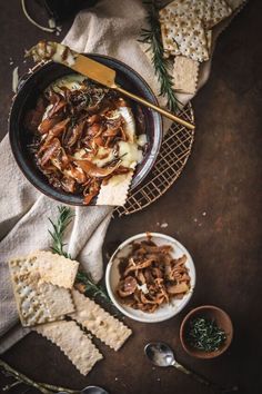 an overhead view of food on a table with crackers and spoons next to it