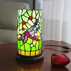 a stained glass lamp sitting on top of a wooden table next to a computer mouse