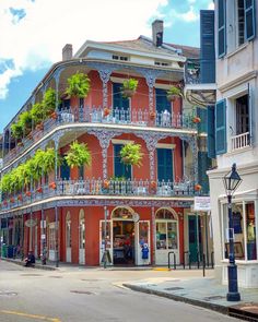 a red building with blue balconies and green plants growing on it's balcony