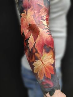 a man's arm with leaves painted on it and the colors of fall are shown