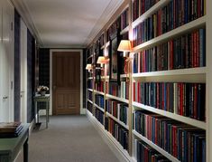 a long bookshelf filled with lots of books next to a lamp on a table