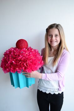 a girl holding a bouquet of flowers in front of a white wall with pink and blue decorations