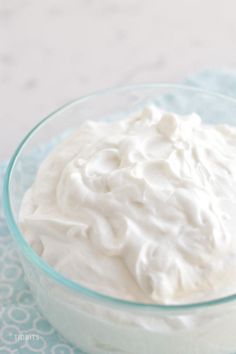 a glass bowl filled with whipped cream on top of a blue and white table cloth