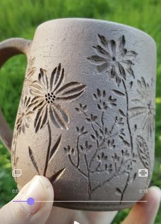 a hand holding a brown mug with flowers on it