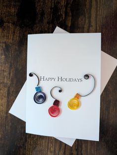 two greeting cards with the words happy holidays written on them next to some spirals