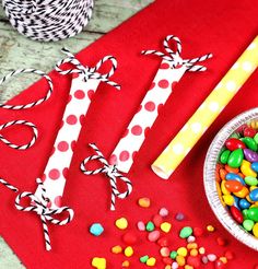 candy and strawberries are sitting on a red place mat next to two striped candles